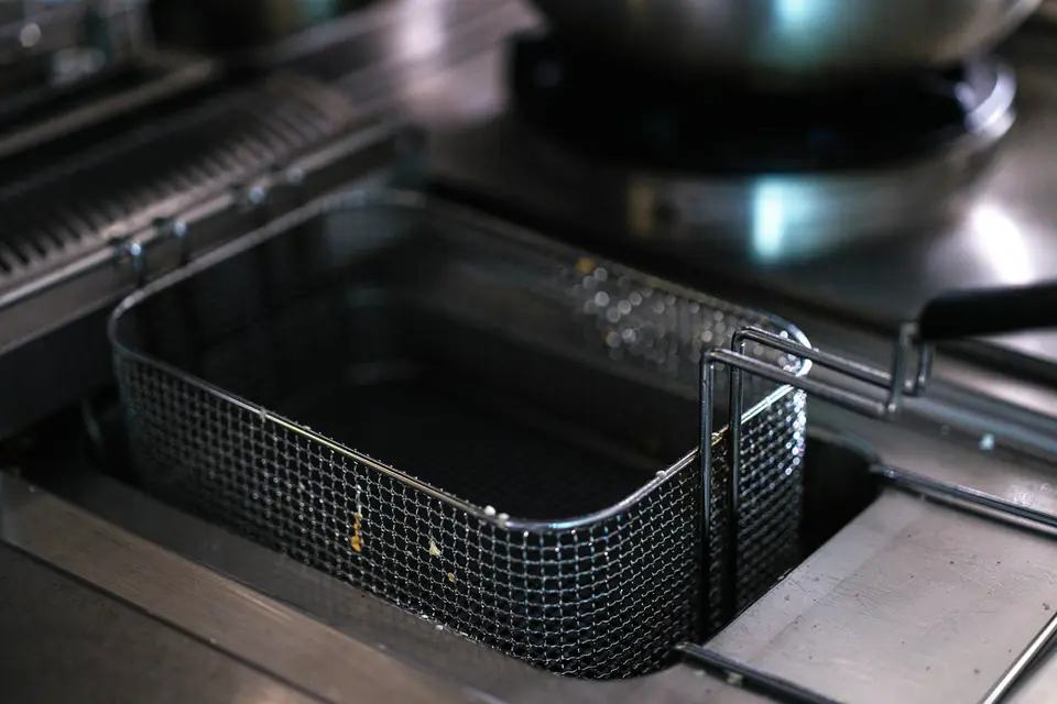 Panier métallique dans le bain d’huile d’une friteuse professionnelle