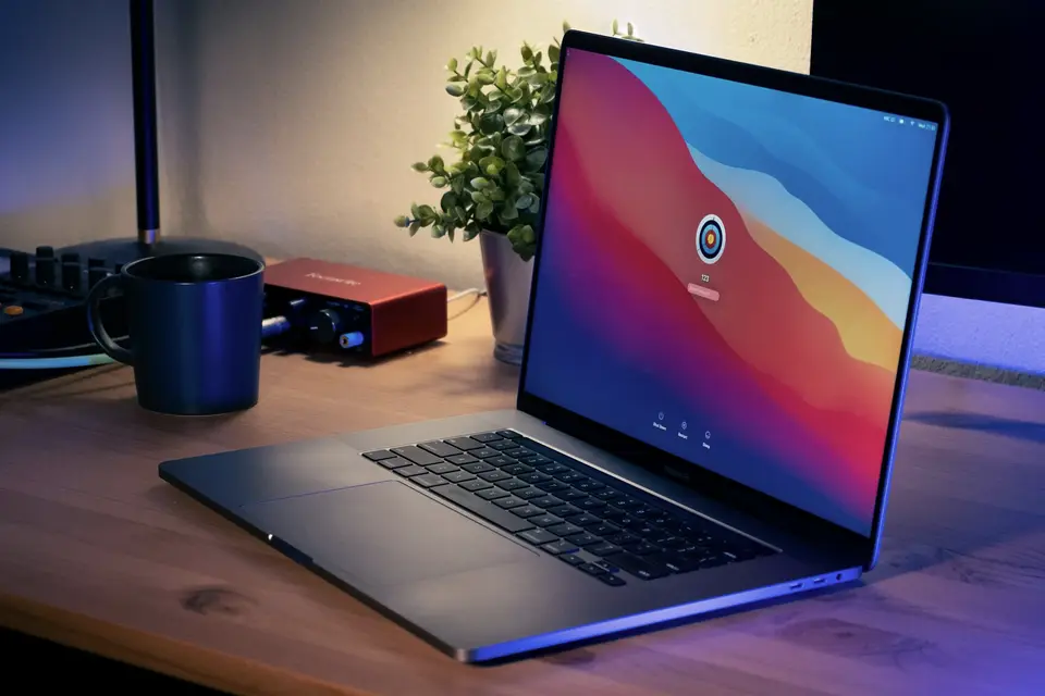 Ordinateur portable ouvert sur un bureau en bois, à côté d’une tasse