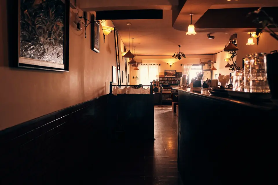 Salle d’un café vide, éclairée par des suspensions, le long du bar