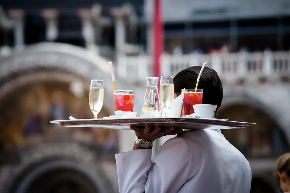 Serveur vu de dos, un plateau de boissons à la main
